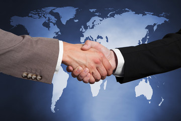 Wall Mural - Businessmen Shaking Hands Against Worldmap