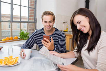 glückliches paar mit zeitung und handy zuhause