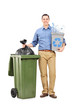 Man holding a recycle bin by a trash can