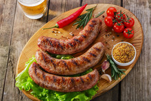 Grilled Sausage On A Board With Vegetables And Sauce