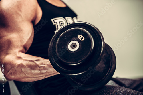Obraz Dibond Hnadsome młody człowiek poćwiczyć z hantlami w fitness - powe