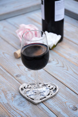 Fotomurales - glas rode wijn op houten tafel met hart decoratie en roosjes