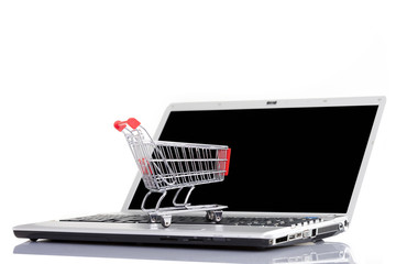 Shopping cart over a laptop computer, isolated on white backgrou