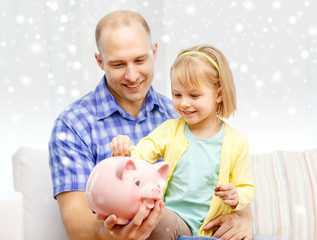 Wall Mural - happy father and daughter with big piggy bank