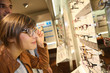 Young woman in optical shop trying eyeglasses on