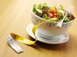 A bowl of mixed salad with a tape measure for healthy eating