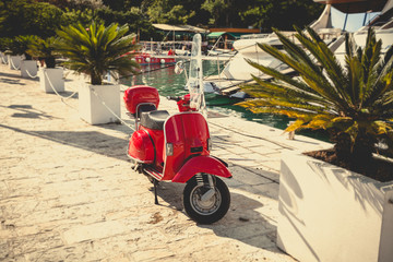 Toned photo of retro red scooter parked at port