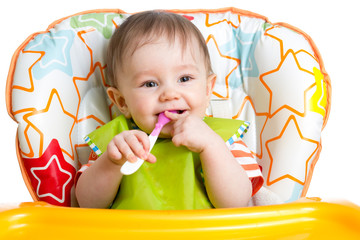 Wall Mural - happy baby child sitting in chair with a spoon