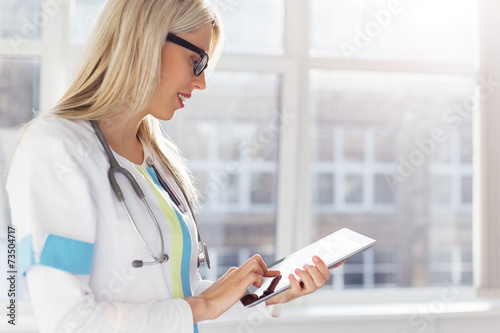 Fotografia, Obraz Female doctor looking at medical records on tablet computer