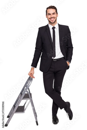 Fotografía Smiling businessman leaning on stepladder