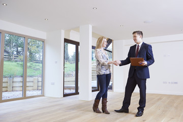 Woman Shaking Hands With Estate Agent In New Home