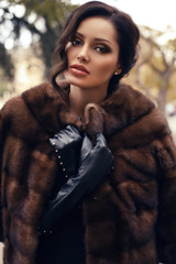 Wall Mural - beautiful woman with dark hair in luxurious fur coat and gloves