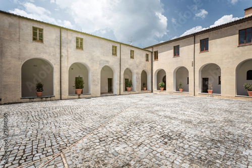 Fotografie, Obraz Empty cobblestone court surrounded by arcades
