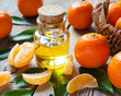 Bottle of essential citrus oil and ripe tangerines with leaves o