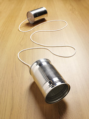 wooden background with two tin cans for communication