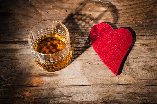Heart and a glass of alcohol on a wooden table in the bar