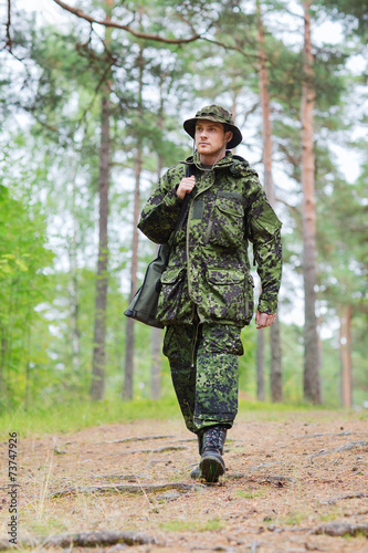 Fotografía young soldier or hunter with gun in forest