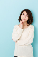 Wall Mural - attractive asian woman thinking on blue background