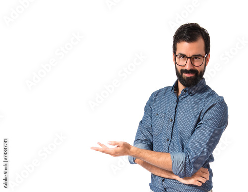 Fotografía Young hipster man presenting something over white background