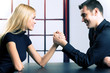 Couple or businesspeople fighting in arm-wrestling
