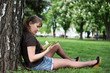 © lexmomot - Young woman reading a book in the city park