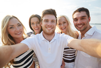 Canvas Print - happy friends on beach and taking selfie