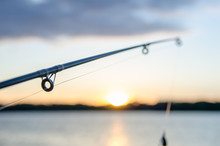 Fishing Rod With Lure At Sunset Over A Lake