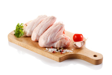 Raw chicken wings on cutting board on white background