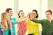 © Syda Productions - smiling students making high five gesture sitting