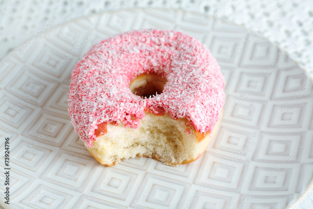 Bitten delicious donut on plate close-up