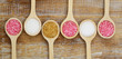 White, brown and pink sugar on wooden spoons on rustic wood