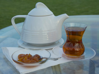 cup of black tea with teapot in the background