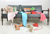 Fototapeta Paryż - Messy clothes, lady bag and shoes scattered on a leather sofa