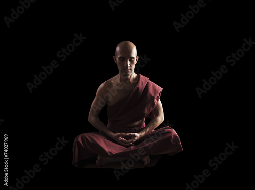 Fotomural buddhist monk in meditation pose over black background