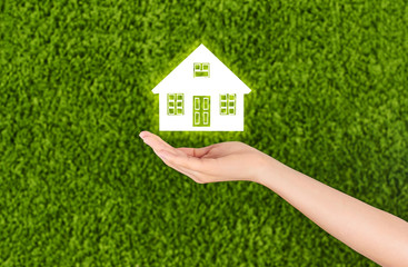 Wall Mural - Hand Holding a house isolated on green background.