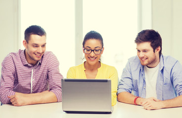 Wall Mural - three smiling colleagues with laptop in office