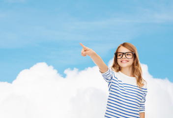 Poster - cute little girl in eyeglasses pointing in the air