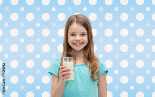 Fototapeta na wymiar smiling girl with glass of milk over polka dots