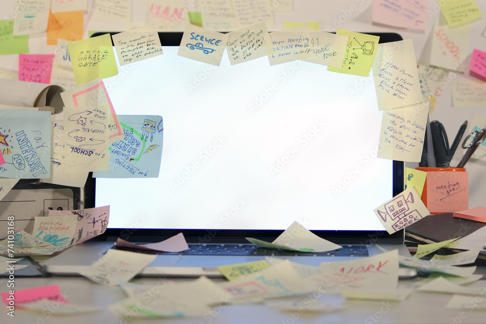 Office desk with laptop covered by post it papers