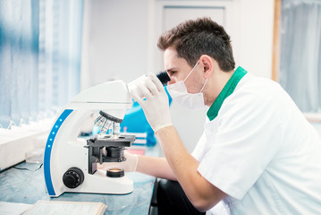 Male scientist, chemist working with microscope in laboratory