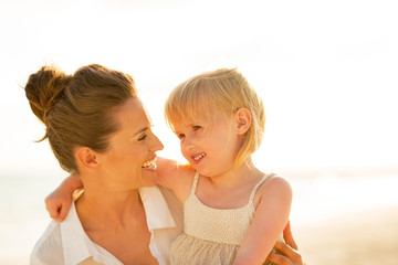 Wall Mural - Portrait of happy mother and baby girl on beach at the evening