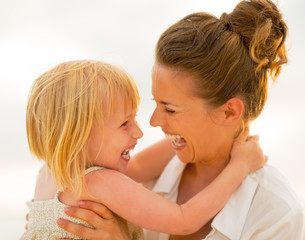 Wall Mural - Portrait of smiling mother and baby girl hugging on beach