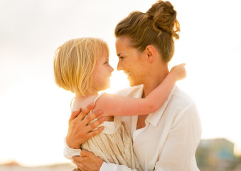 Wall Mural - Portrait of happy mother and baby girl hugging on beach 