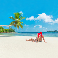 Wall Mural - Happy couple in christmas hats at tropical sandy palm beach