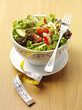 A bowl of mixed salad with a tape measure