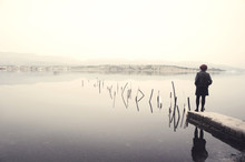Woman In Black Standing On Jetty In A Lake