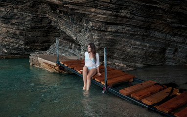 young woman in white shirt sitting in sea cave