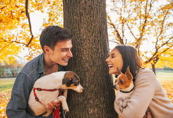 Portrait of happy young couple with dogs outdoors in autumn park