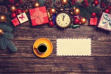 Hot coffee with letter near christmas gifts on wooden table.