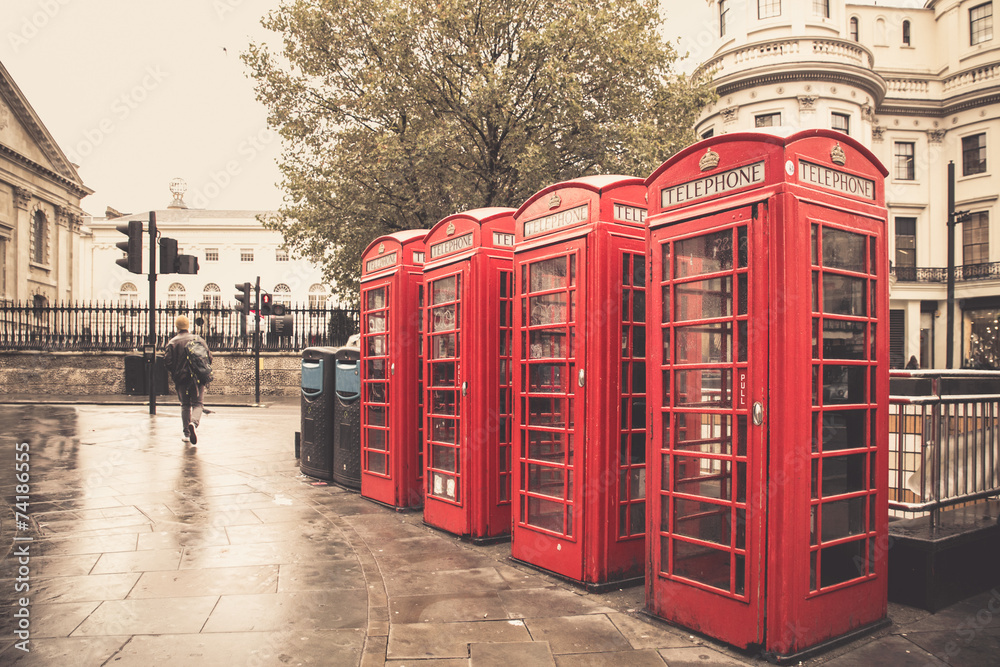 Vintage style  red telephone booths on rainy street in London - obrazy, fototapety, plakaty 